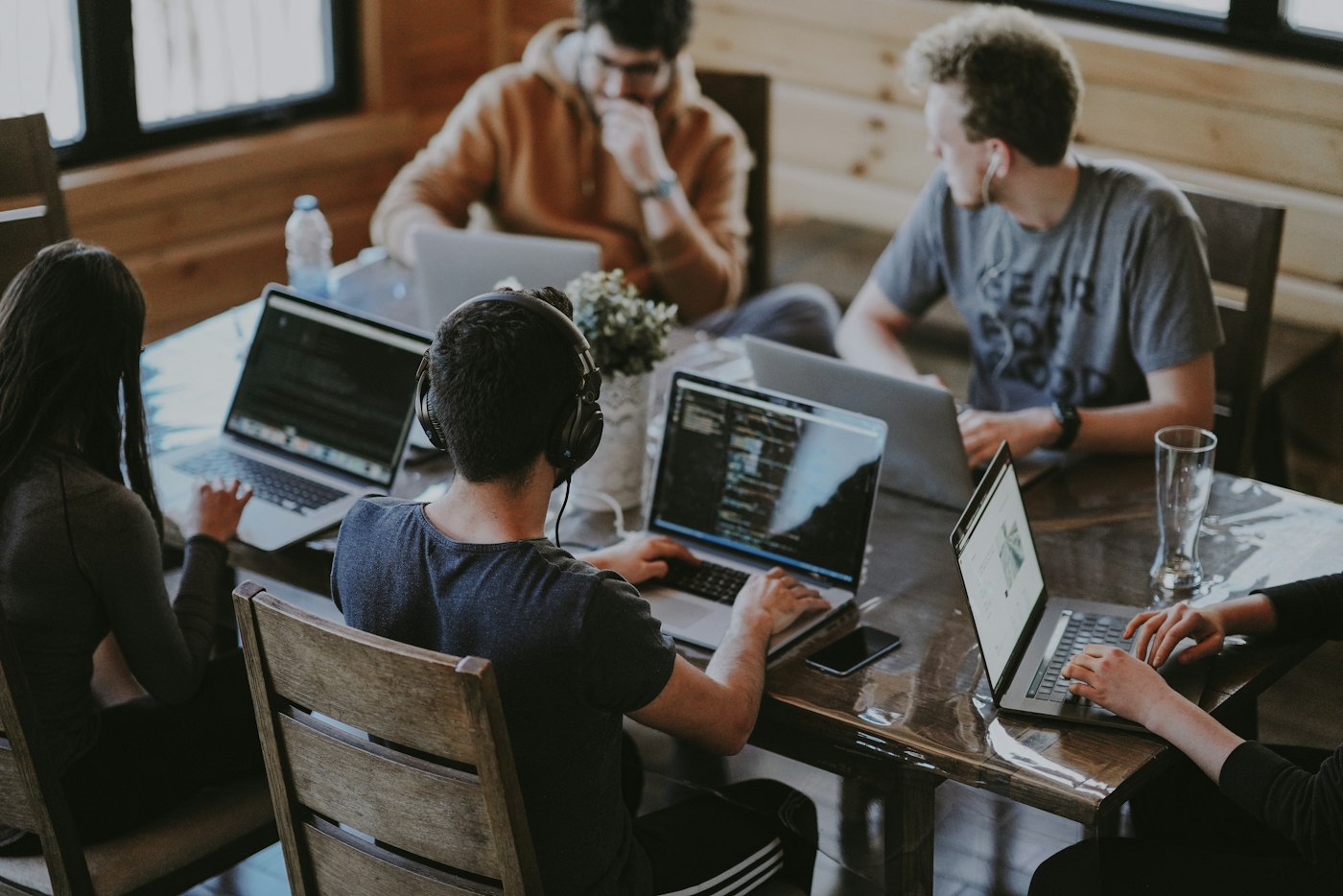 Equipo de trabajo con portátiles alrededor de una mesa de madera en una oficina luminosa