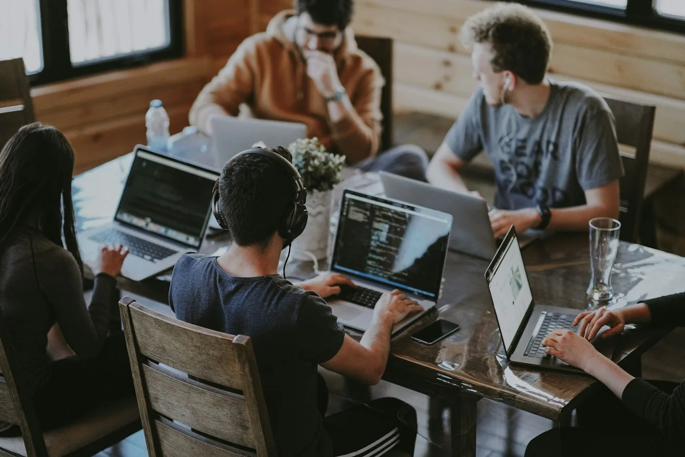 Equipo de trabajo con portátiles alrededor de una mesa en una oficina
