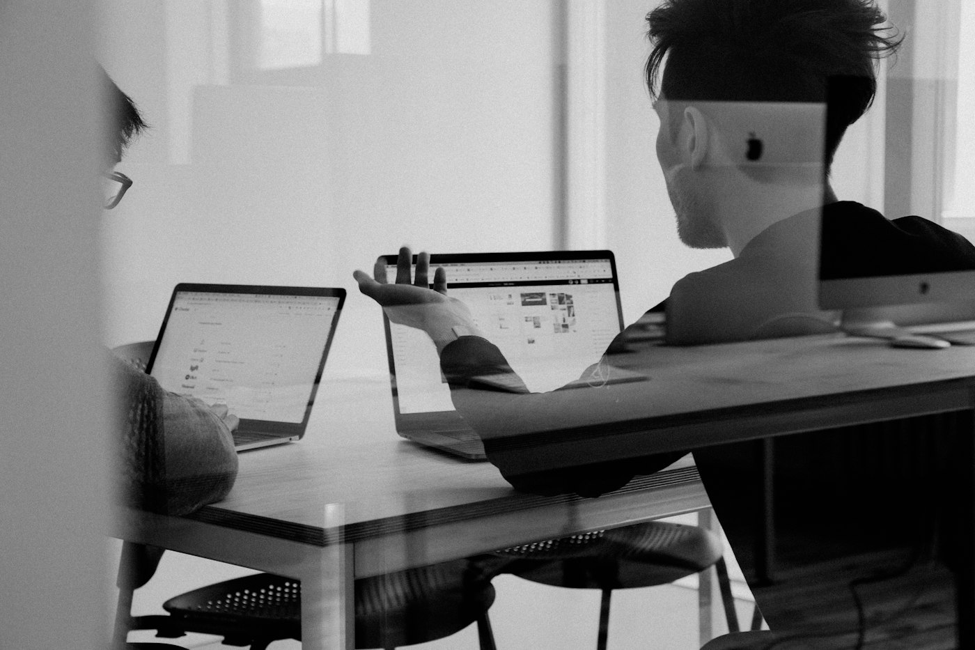 Dos personas trabajando con portátiles en una oficina, fotografía en blanco y negro